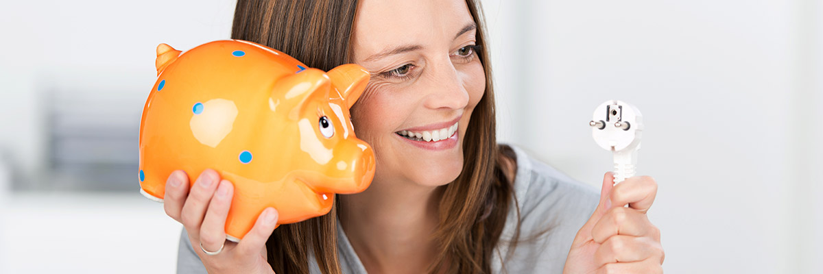 femme avec une tirelire et une fiche électrique satisfaite de ses économies