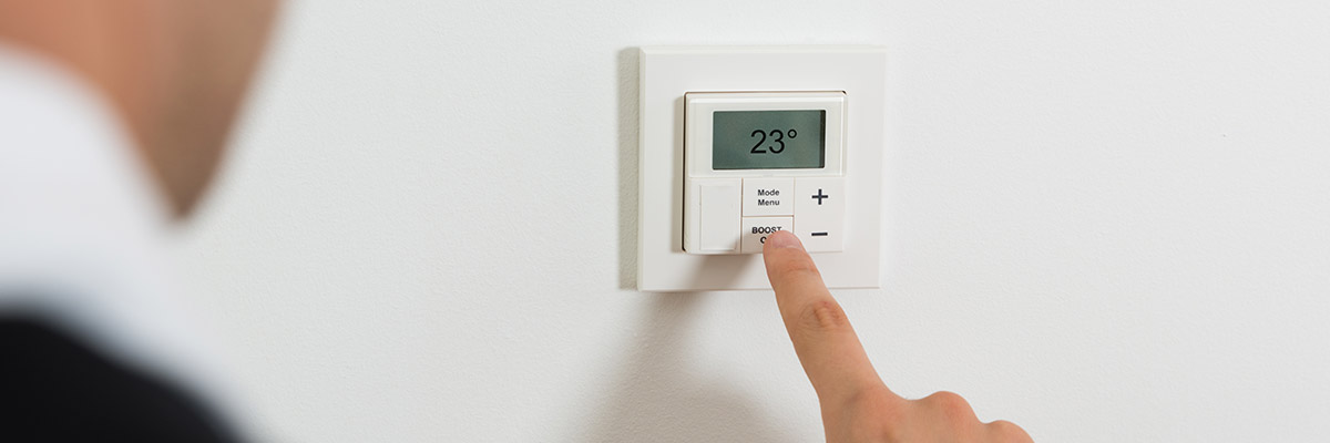 un doigt posé sur un thermostat intérieur