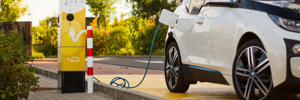 Une voiture blanche est en train de faire le plein via une borne de recharge électrique 